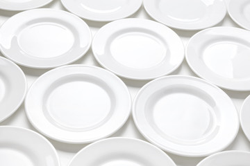Many white plates on table, pattern of dishes