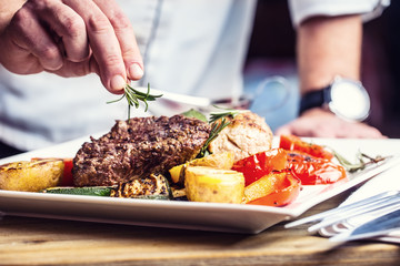 Chef dans une cuisine d& 39 hôtel ou de restaurant cuisinant uniquement les mains. Steak de boeuf préparé avec décoration végétale.