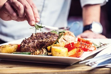 Papier Peint photo Plats de repas Chef dans une cuisine d& 39 hôtel ou de restaurant cuisinant uniquement les mains. Steak de boeuf préparé avec décoration végétale.