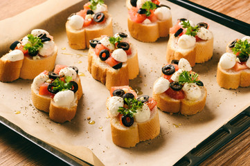 Toasts with mozarella, tomatoes, olives and garlic. Cooking process.