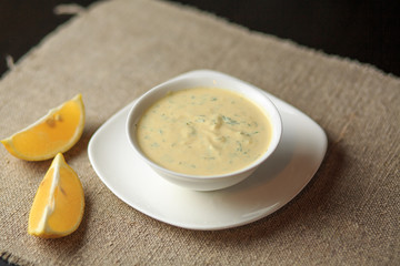 sauce in a plate, mayonnaise in a plate, home-made sauce, sauce Caesar, a lemon, greens