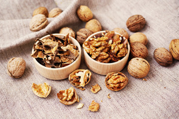 Kernels and partitions of walnut in wooden bowls and the whole walnuts on a table. Walnuts