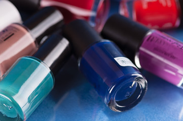 colorful circular bottle with lacquer for nails on a blue background with reflection