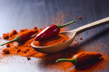 Red chilli peppers on a wooden, black table with spicy. Chilli on a wooden spoon. Vegetable....