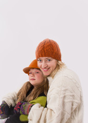 Wonderful mother and daughter hugging sitting in warm knitted clothes