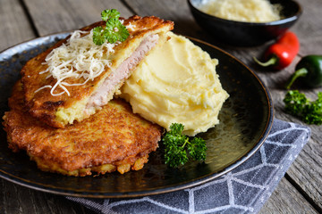 Fried pork cutlets coated in potato batter, studded with cheese and served with mashed potato