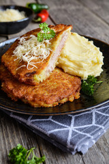 Fried pork cutlets coated in potato batter, studded with cheese and served with mashed potato