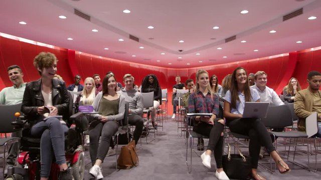 Students sit facing camera in a modern university classroom, shot on R3D