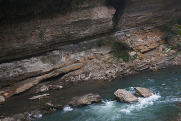 Landscape of rapid mountain river with cracked stone in canyon 