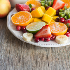 Vegan breakfast: variety of fruits, nuts and berries on the white wooden table, selective focus, copt space for text, square