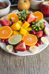 Vegan breakfast: variety of fruits, nuts and berries on the white wooden table, selective focus, copy space for text