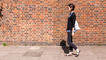 Young trendy woman wearing sandals and black skinny jeans walking in street