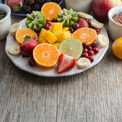 Vegan breakfast: variety of fruits, nuts and berries on the white wooden table, selective focus, copt space for text, square
