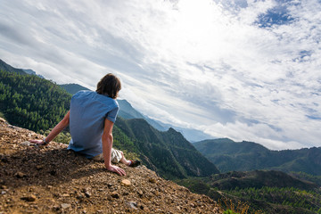 Naklejka premium single man sitting and enjoying the great mountain landscapea