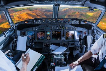 Airplane cockpit flying on colorful Waimea Canyon State Park, also called Grand Canyon of Pacific, at sunset in Kauai, Hawaii, United States, with pilots arms and blank white papers for copy space. - obrazy, fototapety, plakaty