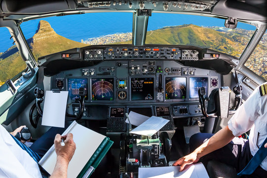 Airplane cockpit flying on Lion's Head, coast and Cape Town in South Africa, with pilots arms and blank white papers for copy space.