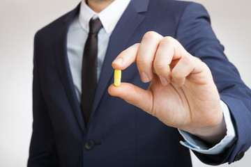 Fototapeta premium Businessman holding pill in hand