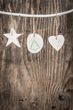 Christmas decorations hanging on branch over rustic wooden background