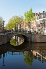 Fototapeta premium Historical bridge over canal with mirror reflections in water, Amstardam, Netherlands