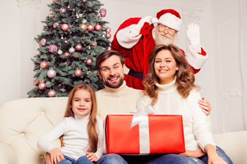 Young cheerful family with daughter holding present from Santa