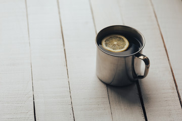 cup of tea with a slice of lemon on a white vintage rustic wooden background. 