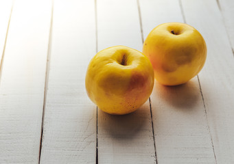 two yellow fresh apples on white rustic wooden background. copy space