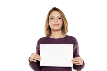 young smiling woman holding a blank sheet of paper for advertising
