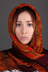 Portrait of girl in a scarf. Close up. Gray background