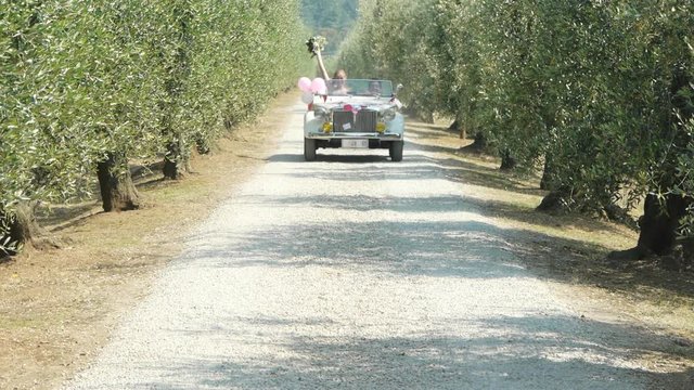 Newlywed couple driving vintage car on country road