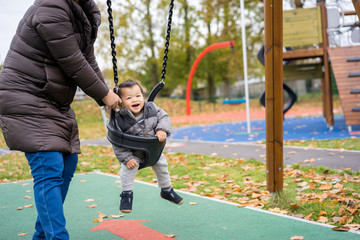 Obraz premium Baby and mother paly swing in the park