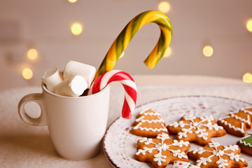 Beautiful Christmas background with gingerbread cookies on white plate with Cup of marshmallows and candy