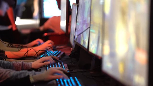 A lot of teenagers playing on computer games. Close-up of hands with keyboards and mouses.