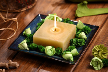 Fototapeta na wymiar Aromatic rustic candle with green sola flowers and potpourri on wodden table