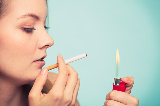 Girl using lighter to light cigarette.