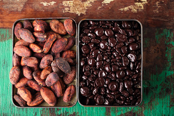 chocolate drops and roasted cocoa chocolate beans  wood backgrou
