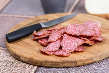 Sliced sausages on the wooden board with bread