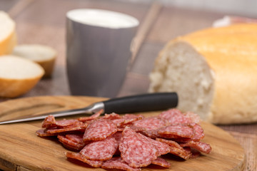 Sliced sausages on the wooden board with bread
