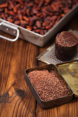 grated dark chocolate in tin with cocoa beans and solid piece in