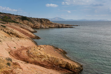 Fototapeta na wymiar Red rocky shores of the Aegean sea, Athens, Greece.