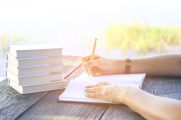 Stock Photo:.female hands with pen writing on notebook on wooden