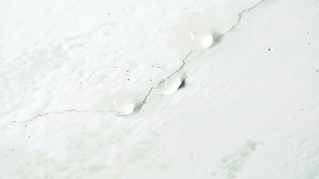 Water drips from ceiling. Faulty water supply in high-rise building. Cracked plaster on the ceiling.