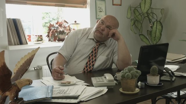 Ungraded: Boss Desk / Manager Office / Boss Doing Nothing / Creative Thinking / No Ideas. Funny fat chief is out of ideas. Man puts the paper sheet aside and begins to dream in the workplace.