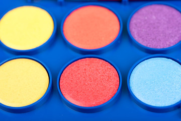 Set of watercolors in the box on a grey wooden table. Palette of water color paints . Closeup.