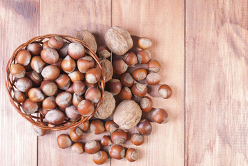 Walnuts and hazelnuts in a basket on wooden background. The view from the top.