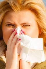Sneezing woman into handkerchief, outside sunny shot