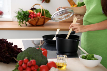 Young woman is cooking by the stove in the kitchen, close up.
