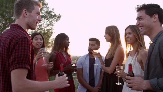 Adult friends socialising at a party on a rooftop at sunset, shot on R3D