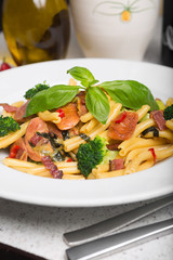 A delicious fresh gourmet Italian strozzapreti pasta dish, with pancetta, italian sausage, broccoli, vegetables, topped with fresh basil.