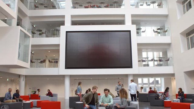 Students and AV screen in atrium at a university, tilt shot