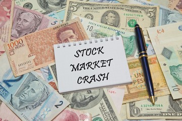 Notebook page with text STOCK MARKET CRASH, background from different world Currencies